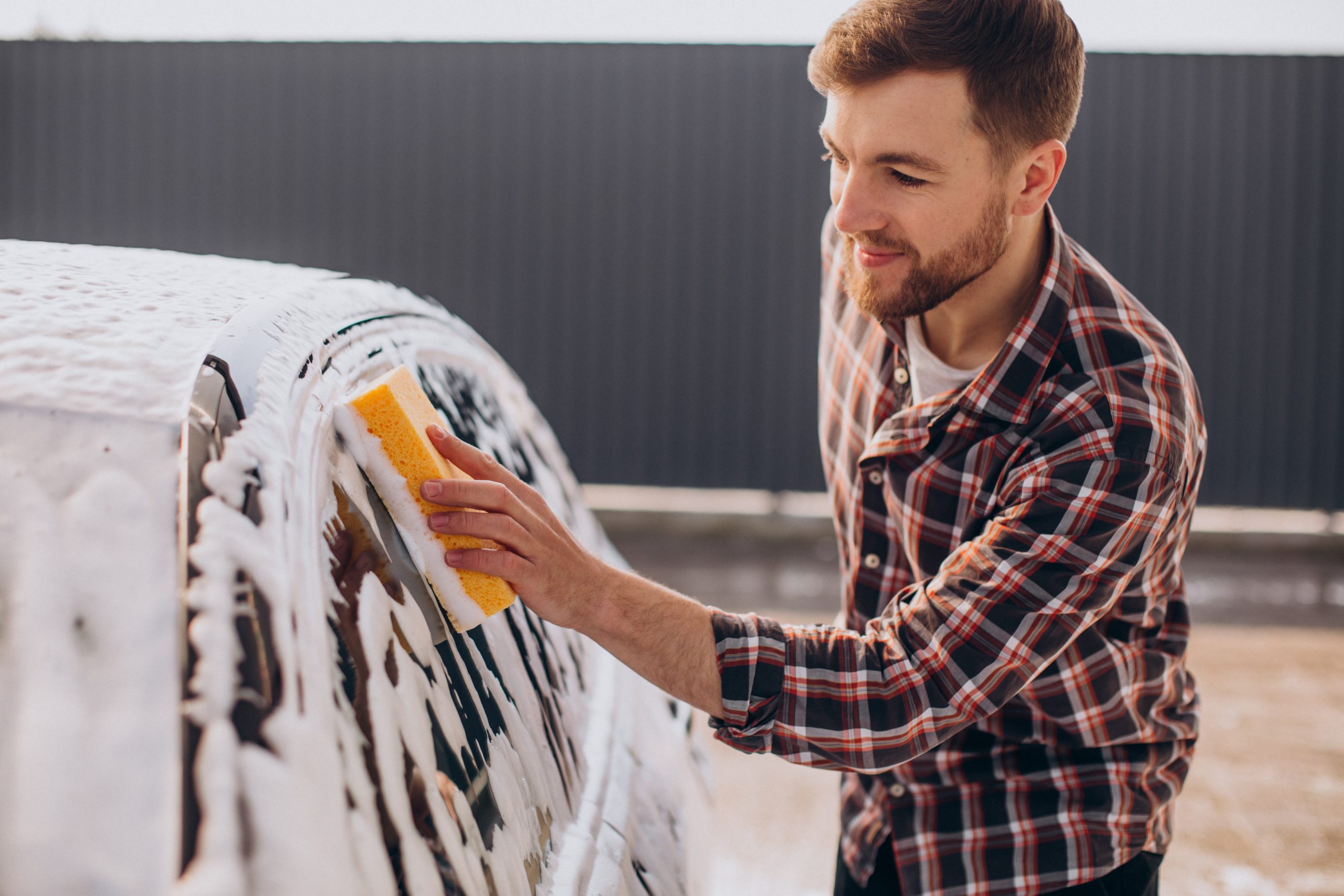 Young man washing his car at carwash